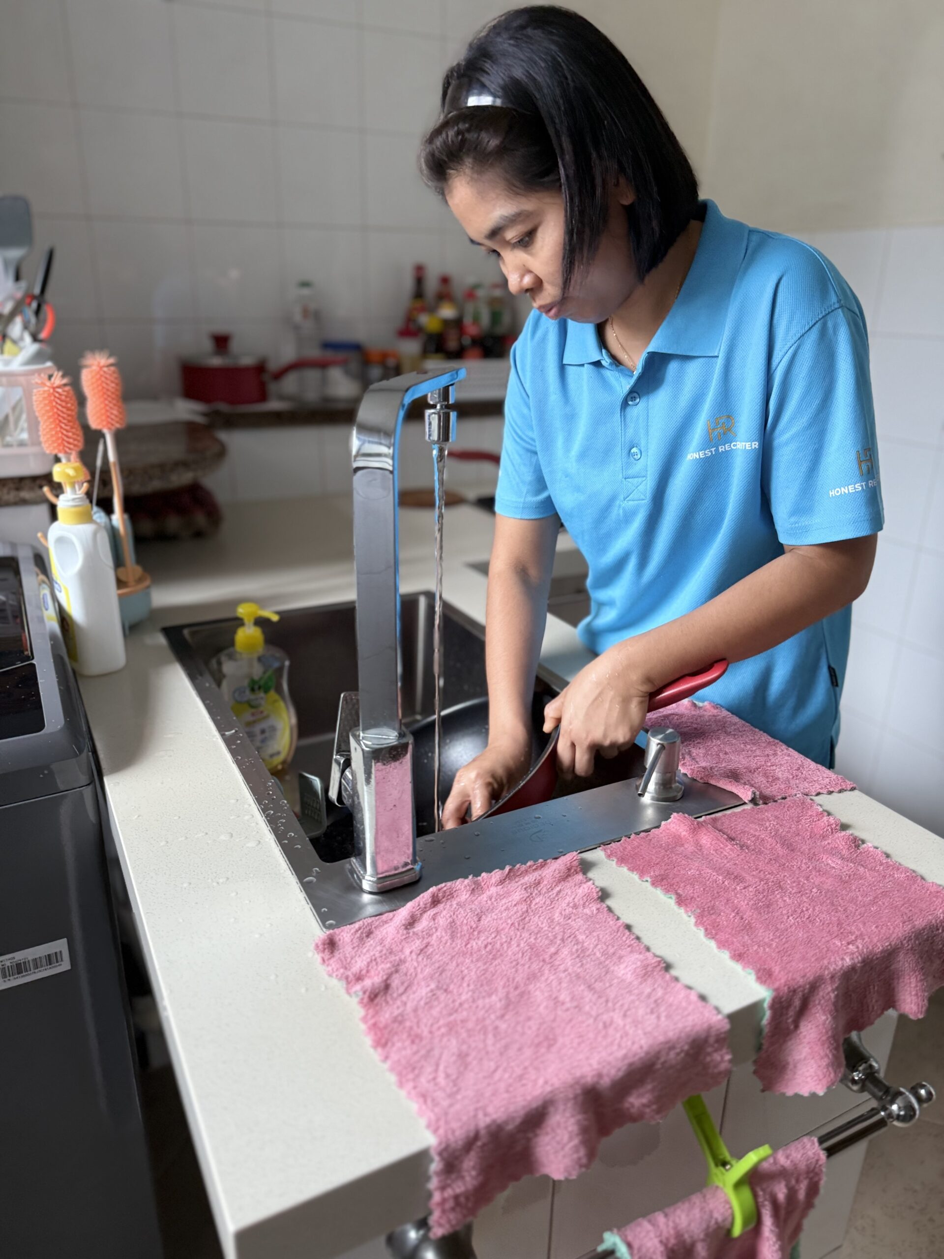 Honest Recruiter cleaner washing dishes in a residential kitchen during home cleaning service in Singapore.