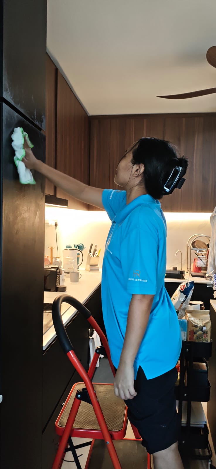 Honest Recruiter part-time cleaner wiping kitchen cabinets during a home cleaning service in Singapore.