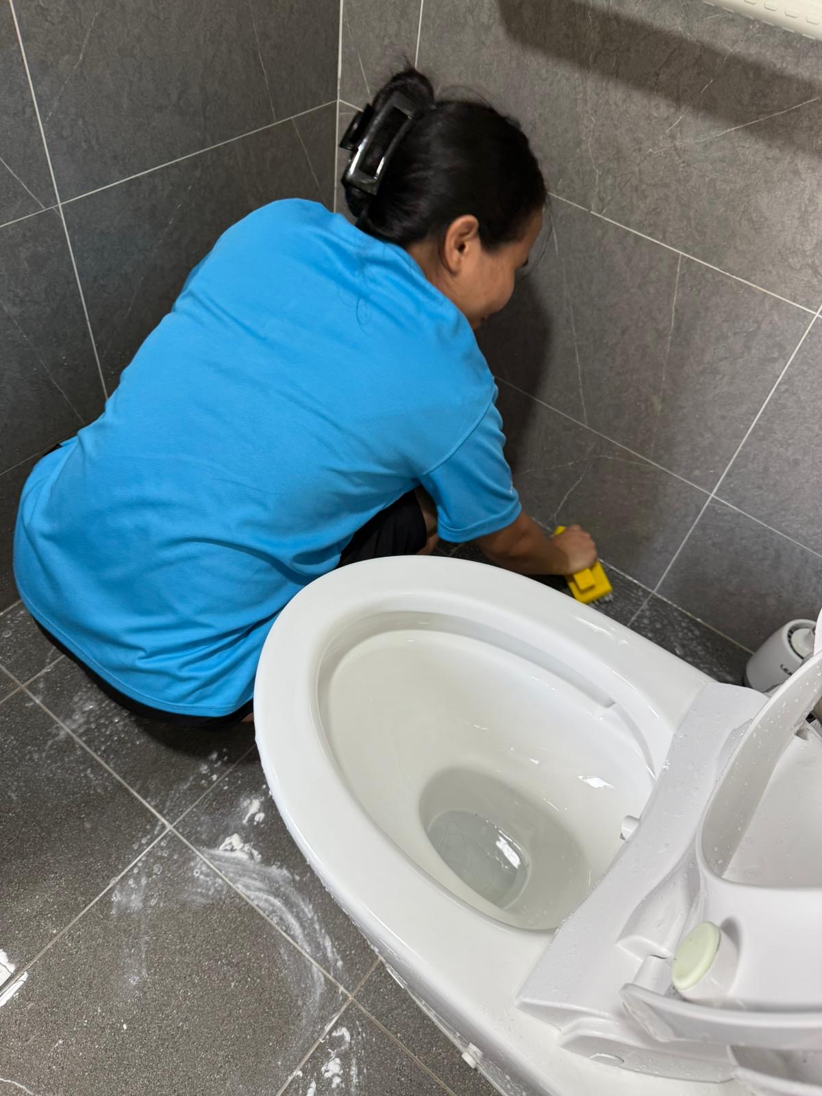 Honest Recruiter cleaner scrubbing a toilet and bathroom tiles during part-time home cleaning service.